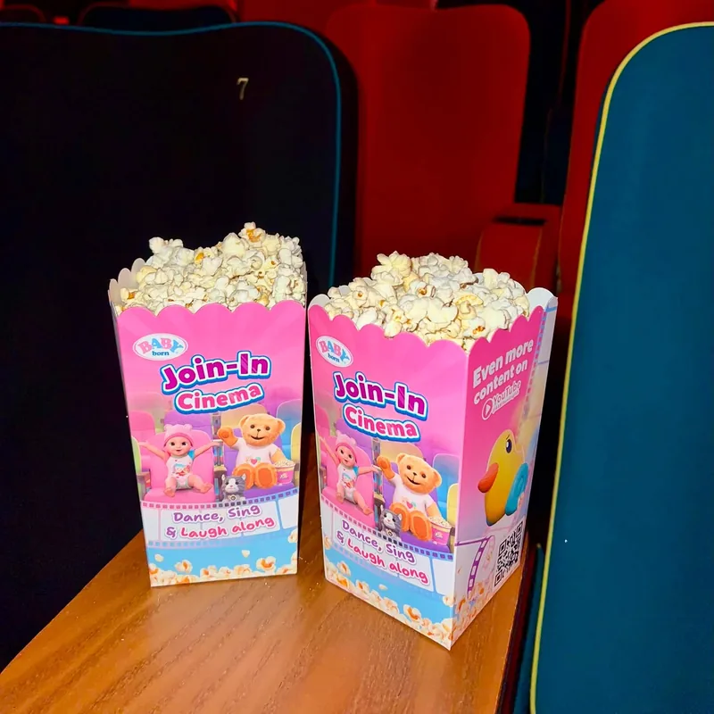 Pink branded popcorn cartons beside cinema seats